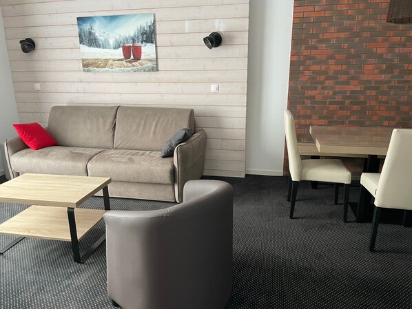 A modern living room with a sofa, a coffee table, and a dining table with chairs. - Studio cabin Gourette 6 ppl with pool and pets allowed (Gourette)