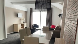 A hotel room with a dining table, chairs, a sofa, a TV, and a lamp. - Studio cabin Gourette 6 ppl with pool and pets allowed (Gourette)