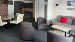 A modern living room with a sofa, armchairs, and a coffee table. There is a kitchen area with cabinets and a microwave. - Studio cabin in Gourette, 6 people, pool, pets allowed (Gourette)