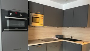 A modern kitchen with grey cabinets, a built-in oven, a microwave, and a sink. - Studio cabin in Gourette, 6 people, pool, pets allowed (Gourette)