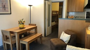 En kompakt opholdsstue med spiseplads, tekøkken og hyggeligt siddeområde.