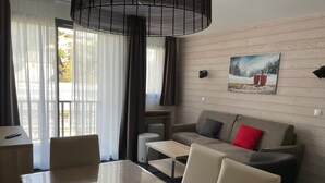 Una habitación de hotel moderna con una mesa de comedor, un sofá y un cuadro en la pared.