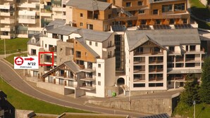 Un edificio residencial de varios pisos con una mezcla de estilos arquitectónicos modernos y tradicionales, que cuenta con balcones y paneles solares.