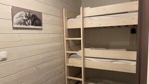Habitación con literas de madera, un estante y un interruptor de luz en la pared.