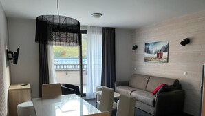 Una habitación de hotel moderna con comedor, sofá y un cuadro en la pared.