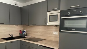 A modern kitchen with grey cabinets, a black oven, and a wooden countertop. - Gourette: 2-Room Apt, 6 People, Pool, Pets Allowed (Gourette)