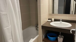 A bathroom with a bathtub, a sink, a mirror, and a shelf with a blue basin and a white basket. - Gourette: 2-Room Apt, 6 People, Pool, Pets Allowed (Gourette)