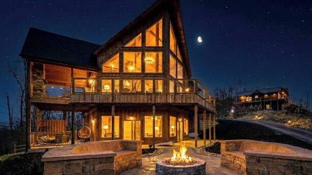 A multi-story wooden cabin with a fire pit in the center, surrounded by stone walls. - Ritzy Bear Lodge, Game Room, Mountain Views, WIFI, Fireplace on deck!!! (Sevierville)