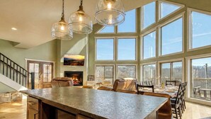 A spacious kitchen with a large island, a fireplace, and large windows offering a view. - Ritzy Bear Lodge, Game Room, Mountain Views, WIFI, Fireplace on deck!!! (Sevierville)