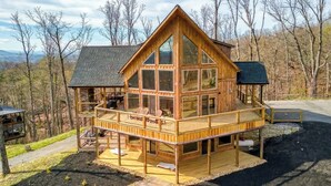 A wooden cabin with a balcony, a fire pit, and a deck. - Ritzy Bear Lodge, Game Room, Mountain Views, WIFI, Fireplace on deck!!! (Sevierville)