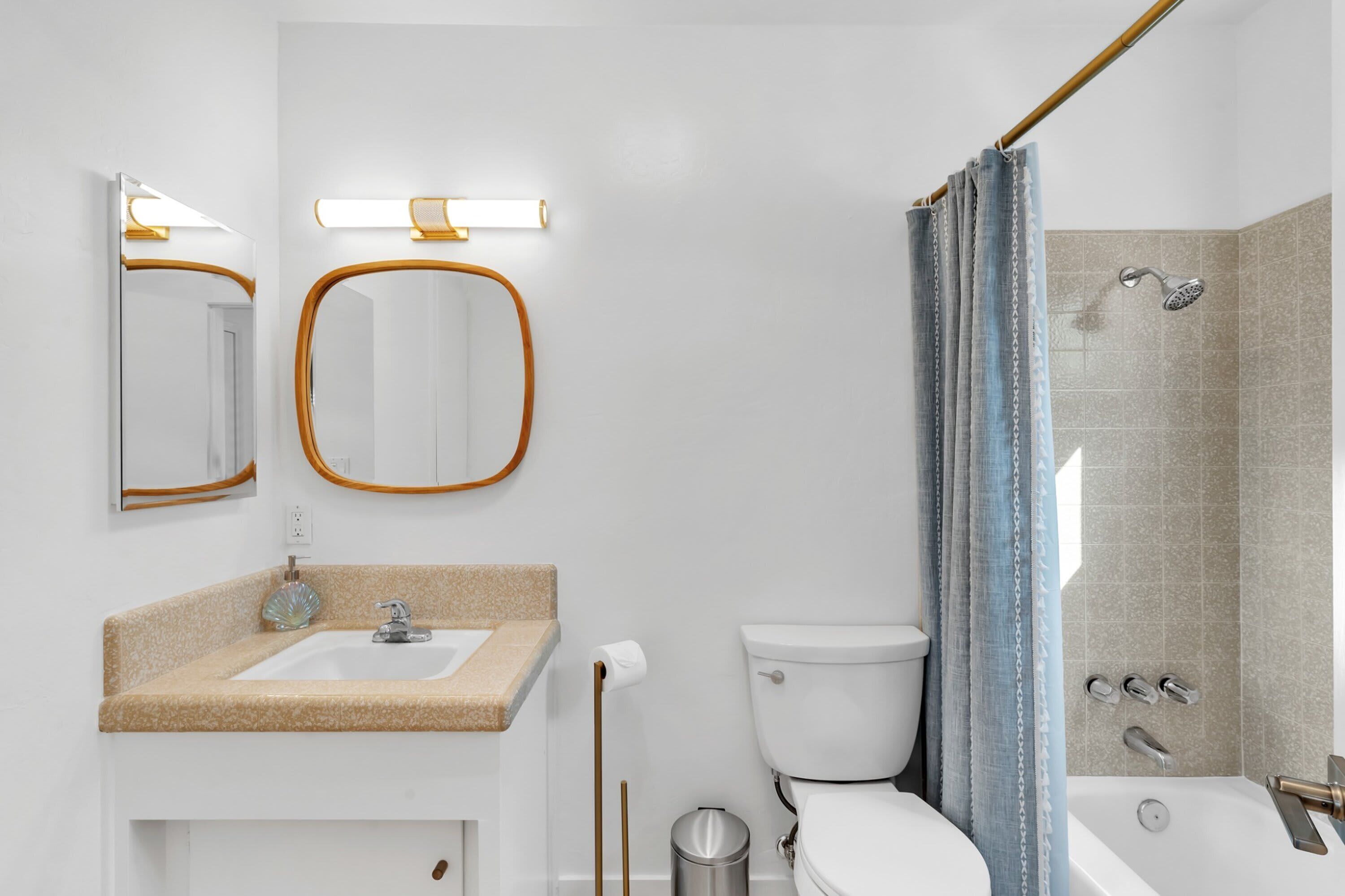 Een moderne badkamer met een wastafel, toilet, douche en twee spiegels.