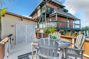 Eine Terrasse mit einem runden Tisch und vier weißen Adirondack-Stühlen, einer weißen Garagentür sowie einem mehrstöckigen Gebäude mit Balkonen.