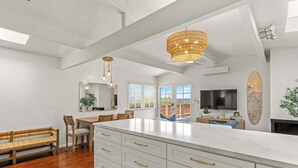 Uma cozinha ampla com uma ilha grande, armários brancos e um lustre moderno.