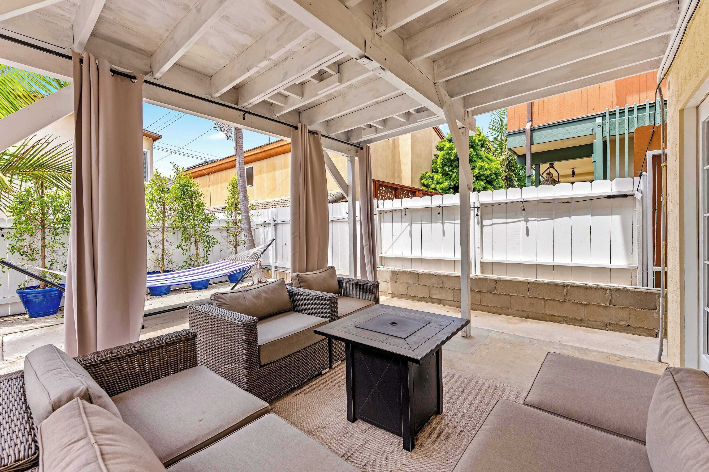 Un espacio de estar al aire libre cubierto con muebles de mimbre, una mesa y vistas del barrio.