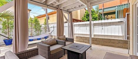Un espacio de estar al aire libre cubierto con muebles de mimbre, una mesa y vistas del barrio.