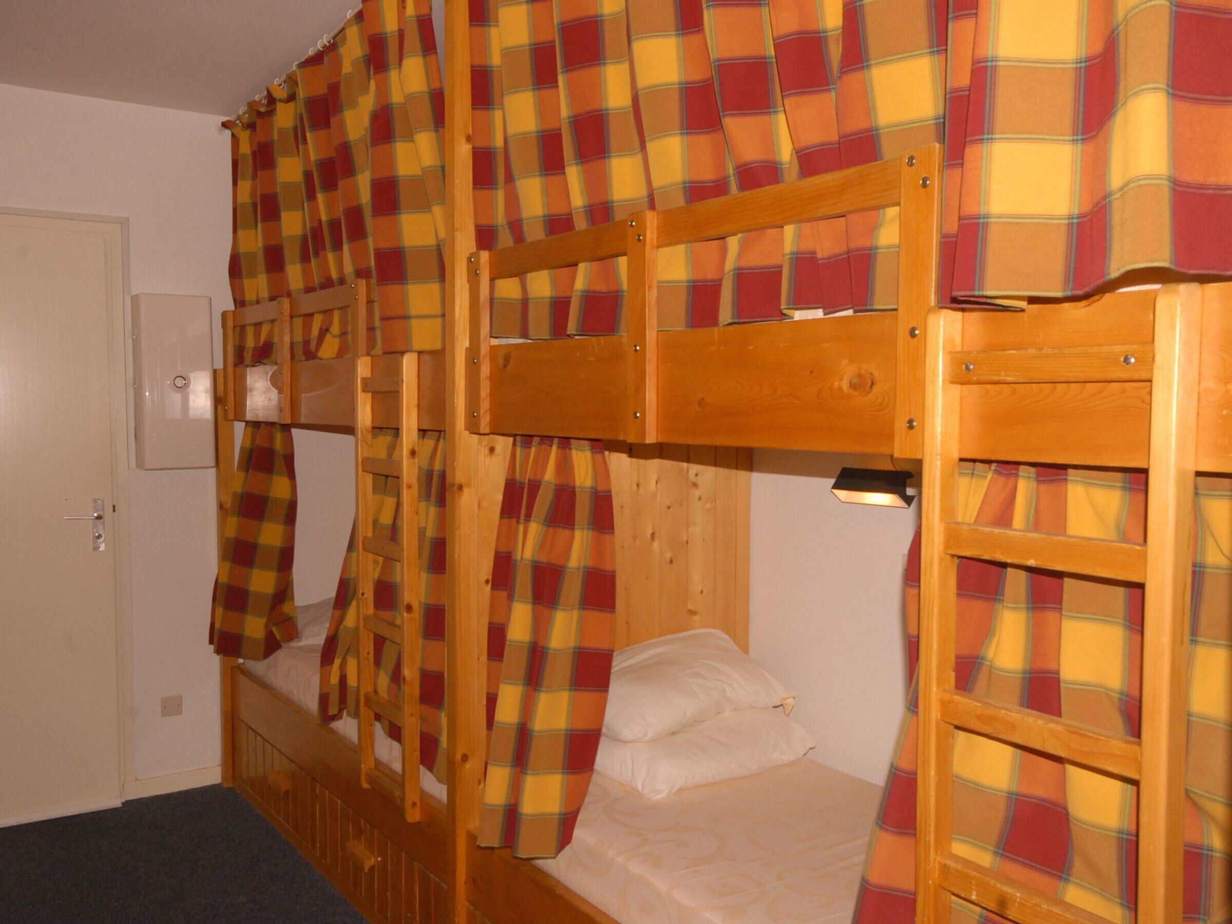 A bunk bed room with plaid curtains and a wooden headboard.