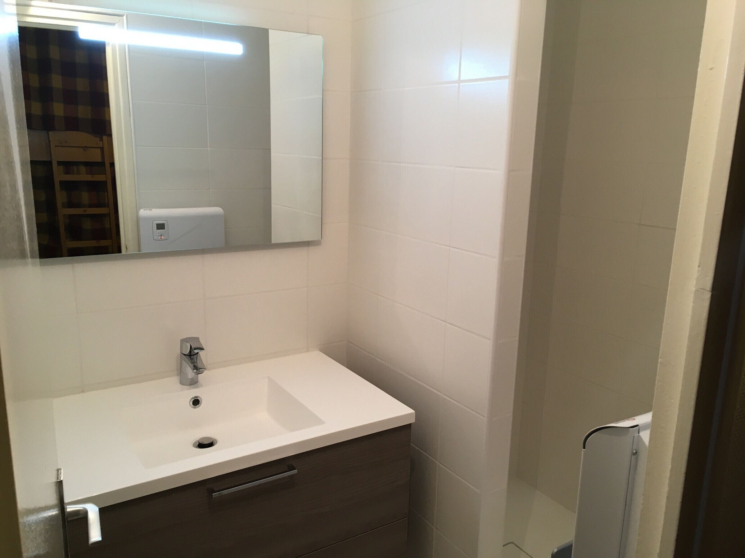 A bathroom with a white sink, a mirror, and a towel rack.