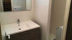 Une salle de bain avec un lavabo blanc, un miroir et un porte-serviettes.