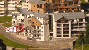 Um edifício residencial moderno com várias varandas, uma entrada notável e uma combinação de estilos arquitetônicos.