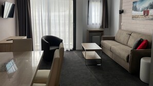 Uma sala de estar moderna com sofá, mesa de centro, poltrona, TV fixada na parede e um quadro na parede.