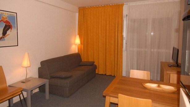 A hotel room with a sofa, a small table, a dining table with chairs, a lamp, and a television. - Comfort studio 6 pers, Gourette resort, pets allowed (Gourette)