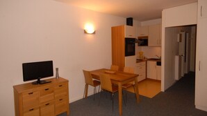A compact living space with a dining area, kitchenette, and a TV on a wooden dresser. - Comfort studio 6 pers, Gourette resort, pets allowed (Gourette)