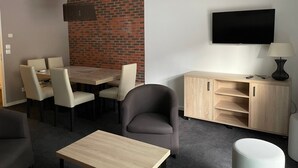 Una habitación moderna con una mesa de comedor, sillas, un sofá, un televisor y un armario.