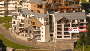 Un edificio residenziale a più piani con balconi, un'area di parcheggio e una strada in primo piano.