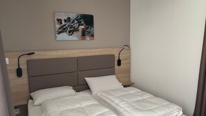 Camera d'albergo con un letto, due comodini, una lampada a parete e un quadro appeso.