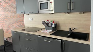 Una cucina moderna con mobili grigi, un forno a microonde, un lavello e un piano di lavoro con un cesto di utensili da cucina.