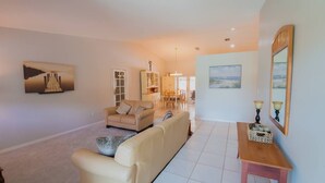 A living room with a sofa, a coffee table, and a dining area with chairs and a table. - ‼️Poolside Miami Paradise w/ BBQ + Outdoor Lounge (Miami)