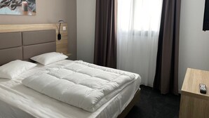 Een hotelkamer met een groot bed, een nachtkastje, een lamp en een schilderij aan de muur.