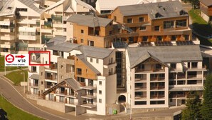 Ein Wohngebiet mit modernen Gebäuden, darunter ein mehrstöckiges Haus mit Balkonen und einer Mischung aus flachen und geneigten Dächern.