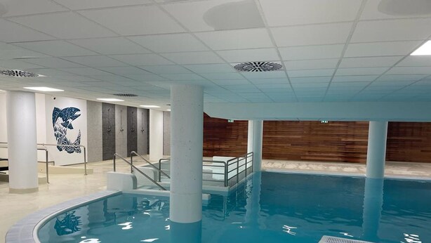 Ein Hallenbad mit einer Holzvertäfelung und einem Wandgemälde eines Wals an der linken Seite.