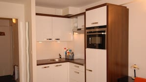Eine kleine Küche mit weißen Schränken, einem Backofen und einem Spülbecken.