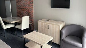 Ett modernt hotellrum med en matplats, en TV som är monterad på väggen och en sittgrupp med en stol.