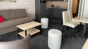 Moderni olohuone, jossa on sohva, sohvapöytä sekä ruokailutila, jossa on tuoli ja pöytä.