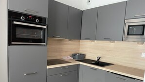 Una cocina moderna con armarios grises, un horno negro, un lavaplatos y un microondas.