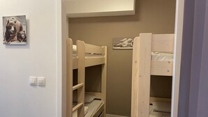 Habitación con literas, dos literas, un estante pequeño con osos de peluche y un cuadro colgado en la pared.