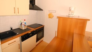 Una cocina compacta con estufa, horno, pileta y encimera de madera.