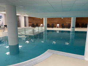 Ein Hallenbad mit einer Holzwand und Stühlen.