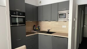 A compact kitchen with grey cabinets, a black sink, and a microwave.