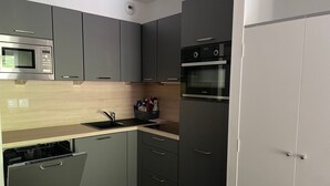 Una cocina moderna con armarios grises, microondas integrado, lavavajillas y horno de acero inoxidable.