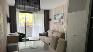A modern hotel room with a glass dining table, a sofa, a desk, and a wardrobe. - Gourette studio pool 4 pers., pets allowed (Gourette)
