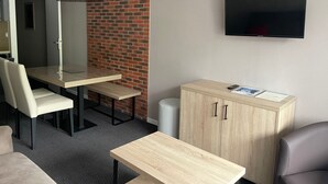 A hotel room with a dining table, chairs, a TV, and a cabinet. - Gourette studio pool 4 pers., pets allowed (Gourette)