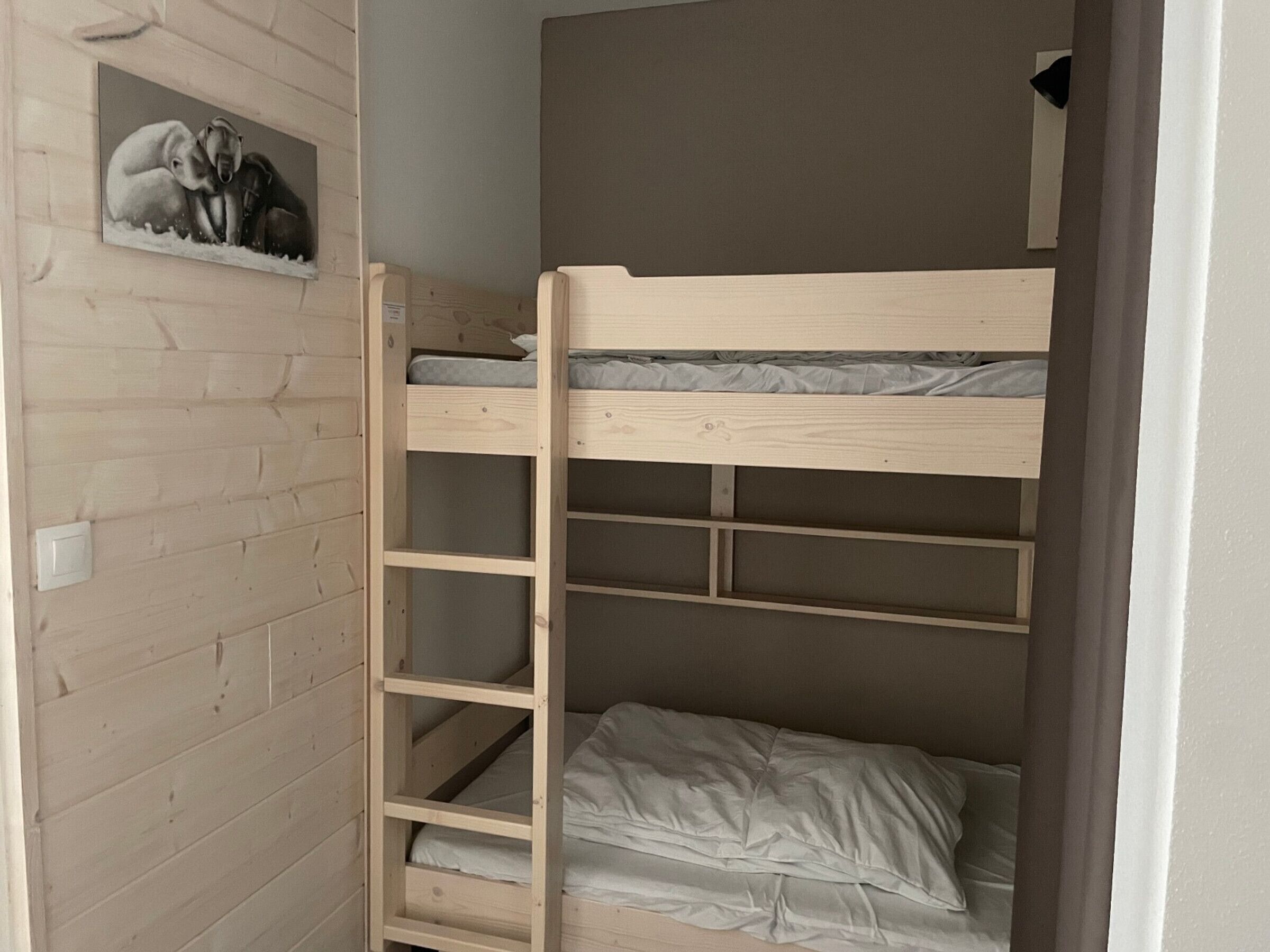 A bunk bed with a wooden frame and a shelf below.