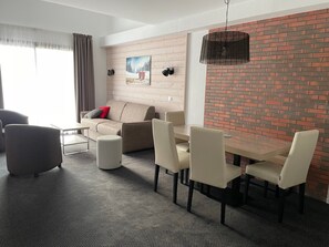 En moderne stue med sofa, spisebord med stole, sofabord og pejs med murstensvæg.