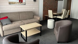 Een moderne woonkamer met een bank, een salontafel en een eethoek met stoelen en een tafel.