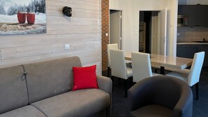 Ein modernes Wohnzimmer mit einer Couch, einem roten Kissen und einem Essbereich mit Tisch und Stühlen.