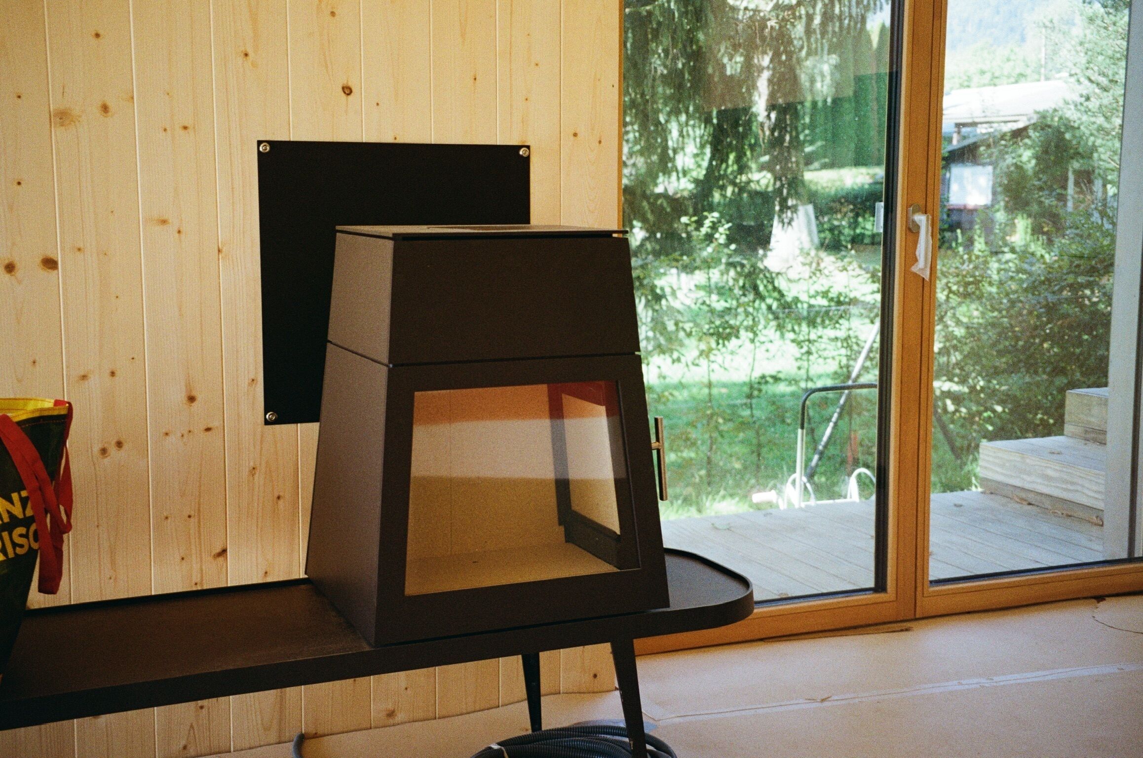 Una stanza con una parete in legno, una porta vetrata che dà sull'esterno e un tavolo con una borsa sopra.
